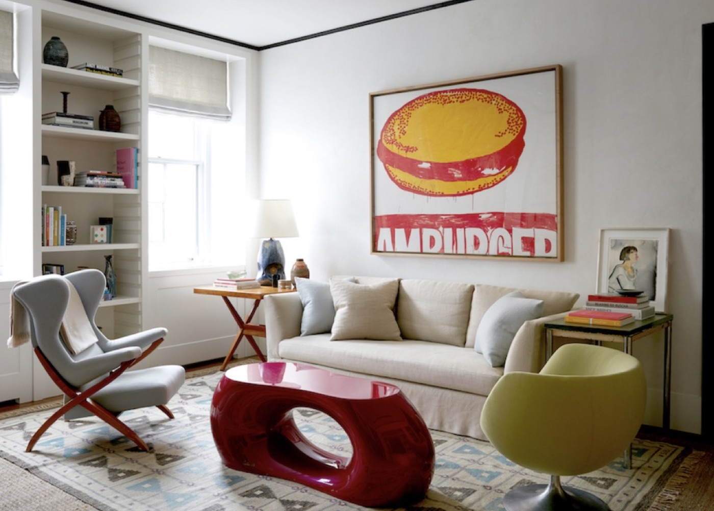 A living room with a cream sofa, red lacquer table and a large framed pop artwork
